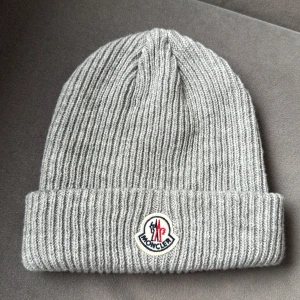 Moncler mössa - Säljer denna Moncler mössa i grå, fin kvalité, aldrig använd. 