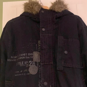 Cool svart vinterjacka - Säljer en fodrad svart jacka i jeansliknande material med pälsdetaljer på huvan🔥 Jackan har långa ärmar och flera fickor med knappar. Den är tillverkad i ett robust material och har en dragkedja framtill. Den är i gott skick och jag säljer den på grund av att den tyvärr är för stor för mig 