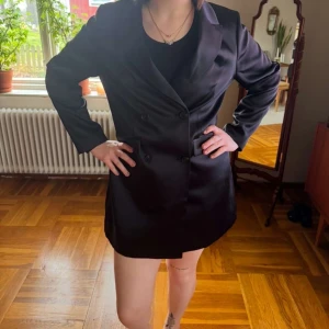 Svart kavajklänning - Snygg svart kavajklänning med dubbelknäppning och långa ärmar. Perfekt för en stilren look. Klänningen har en klassisk krage . Använt endast 1 gång så i mycket bra skick 