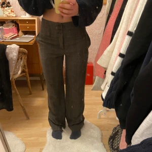 Bruna rutiga kostymbyxor - Snygga bruna kostymbyxor med diskret rutmönster. Byxorna har låg midja och stängs med tre knappar framtill. Dem är raka i modellen. Skriv för måtten❤️