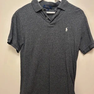 Grå pikétröja från Polo Ralph Lauren - Säljer en klassisk grå pikétröja från Polo Ralph Lauren med den ikoniska loggan broderad på bröstet. 