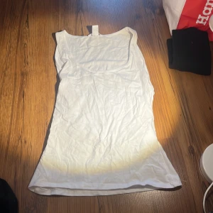 Vit ärmlös linnetopp - Säljer en vit ärmlös linnetopp i bomull. Perfekt för varma sommardagar. Enkel och stilren design.
