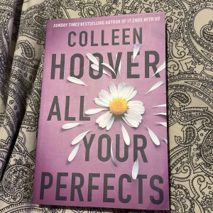 All Your Perfects - Boken 'All Your Perfects' av Colleen Hoover är en gripande roman om kärlekens utmaningar och löften. Omslaget är lila med en prästkrage som dekoration. Perfekt för dig som gillar emotionella och tankeväckande berättelser.