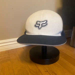 Beige och marinblå keps från Fox - Snygg keps från Fox i beige och marinblått med broderad logga framtill och text på sidan. Pris kan diskuteras!