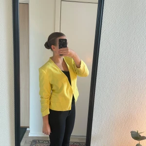 Gul kavaj - Säljer en snygg gul kavaj som är perfekt för att liva upp vilken outfit som helst. Kavajen är stilren och kan bäras både till vardags och fest. Storlek 42 men skulle säga att den passar s