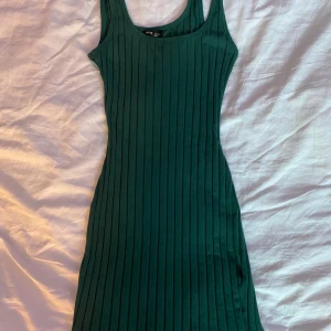 Klänning - Mörkgrön stretchig ribbad klänning med breda axelband. Säljer då den är för liten för mig. Väldigt bekvämt material. Fin och somrig!!