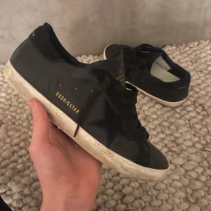 Säljer ett par svarta Golden Goose sneakers i bra skick. De har en cool stjärndetalj på sidan ⭐️ och klassisk snörning. Sulan är vit med en lite sliten look som ger dem en vintage känsla. Perfekta för både vardag  och fest!🥳🎉 Kom gärna privat 🕵️‍♂️ifall de e några frågor eller annat du behöver!!😊🙌🏼