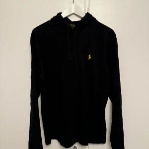 Svart hoodie från Ralph Lauren - Säljer en stilren svart hoodie från Ralph Lauren. Den har en klassisk design med en liten gul logga på bröstet. Perfekt för både vardag och chill. Den är i mycket bra skick och passar perfekt till höst och vinter.