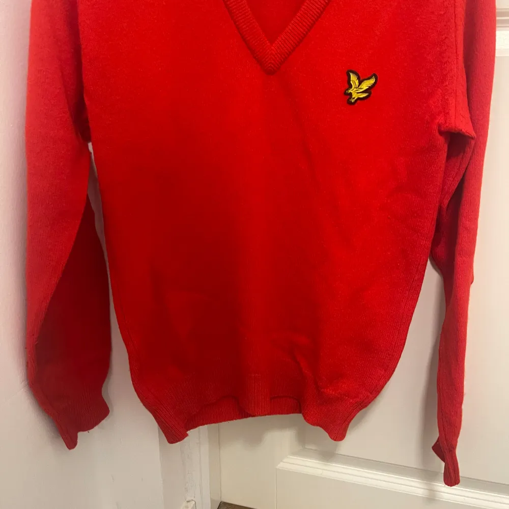 Säljer en snygg röd tröja från Lyle & Scott i 100% lammull. Den har en klassisk v-ringning och ett broderat emblem på bröstet. Perfekt för höst och vinter, håller dig varm och stilren. Tröjan är i mycket bra skick och passar både till vardags och fest. S men passar M. Tröjor & Koftor.