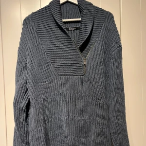 Grå/blå stickad tröja från Tiger of Sweden - Säljer en snygg grå stickad tröja från Tiger of Sweden. En quarterzip tröja med fällbar krage i bra skick. En sample tröja från Tiger of Sweden med nypris 3000:-