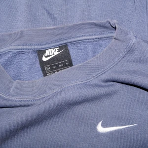 Blå croppad sweatshirt från Nike - Säljer en snygg blå croppad sweatshirt från Nike. Den har en klassisk rund halsringning och det ikoniska Nike-loggan broderad i vitt på bröstet. Perfekt för en avslappnad stil eller träning. Superbekväm och i bra skick!