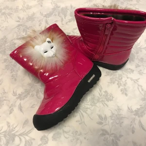 Rosa glansiga vinterstövlar med pälsdetalj - Säljer ett par supercoola rosa glansiga vinterstövlar med pälsdetalj och en söt lejonfigur framtill. De har en praktisk dragkedja på sidan och en robust svart sula för bra grepp. Perfekta för att hålla sig varm och stilren under vintern!        Stlk kvar 27.29,30,31                               Med fleece inuti , rekommenderar att välja en stlk större 