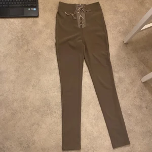 Bruna leggings från Bik Bok - Snygga bruna leggings från Bik Bok i storlek S. De har en hög midja och cool snörning framtill som ger en unik touch. Perfekta för både vardag och fest! Materialet är stretchigt och bekvämt, vilket gör dem till ett måste i garderoben. 🧡