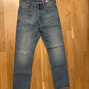 Blå jeans från G-Star RAW - Säljer ett par snygga blå jeans från G-Star RAW i modellen Triple A. De har en regular straight passform och är tillverkade av japanskt tyg. Jeansen har en klassisk femficksdesign och en cool sliten look. Perfekta för en avslappnad stil!