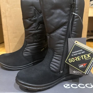Svarta vinterstövlar från Ecco - Snygga och praktiska svarta vinterstövlar från Ecco med Gore-Tex för att hålla fötterna torra. De har en dragkedja på sidan för enkel på- och avtagning och en cool stjärndetalj. Perfekta för kalla och blöta dagar!