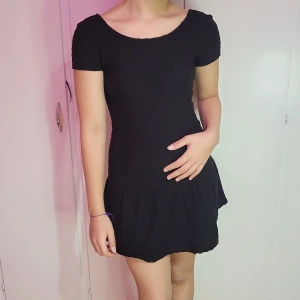 Svart kortklänning - Snygg svart kortklänning i ett enkelt och stilrent snitt. Klänningen har korta ärmar och en rundad halsringning fram, med en djupare öppen rygg. Perfekt för både vardag och festliga tillfällen!