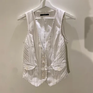 Vit randig kostymväst från Vero Moda - Randig kostymväst i strl 38. Justerbar (se bild 2), så skulle säga strl 36-38. I gott skick!