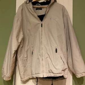 Beige vinterjacka från First Sports Line - Säljer en beige vindjacka från First Sports Line i storlek M. Jackan har dragkedja och huva, perfekt för blåsiga dagar. Den har en sportig look med ett tryck på ryggen. Den är använd men i bra skick :)