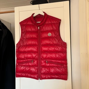 Moncler Gui - Säljer en snygg röd Gui väst från Moncler i mycket bra skick. Perfekt för höst och vår när du vill hålla dig varm men ändå se stilren ut. Passar både till vardags och lite finare tillfällen. Tveka inte att skriva vid frågor och funderingar!