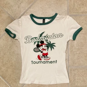 Top med Mussepig tryck stl XSS - Croppad babytee med mussepig tryck och gröna detaljer. Toppen är enbart använd fåtal gånger och är i stl xxs. Klicka gärna på köp nu och meddela för eventuella frågor. :)