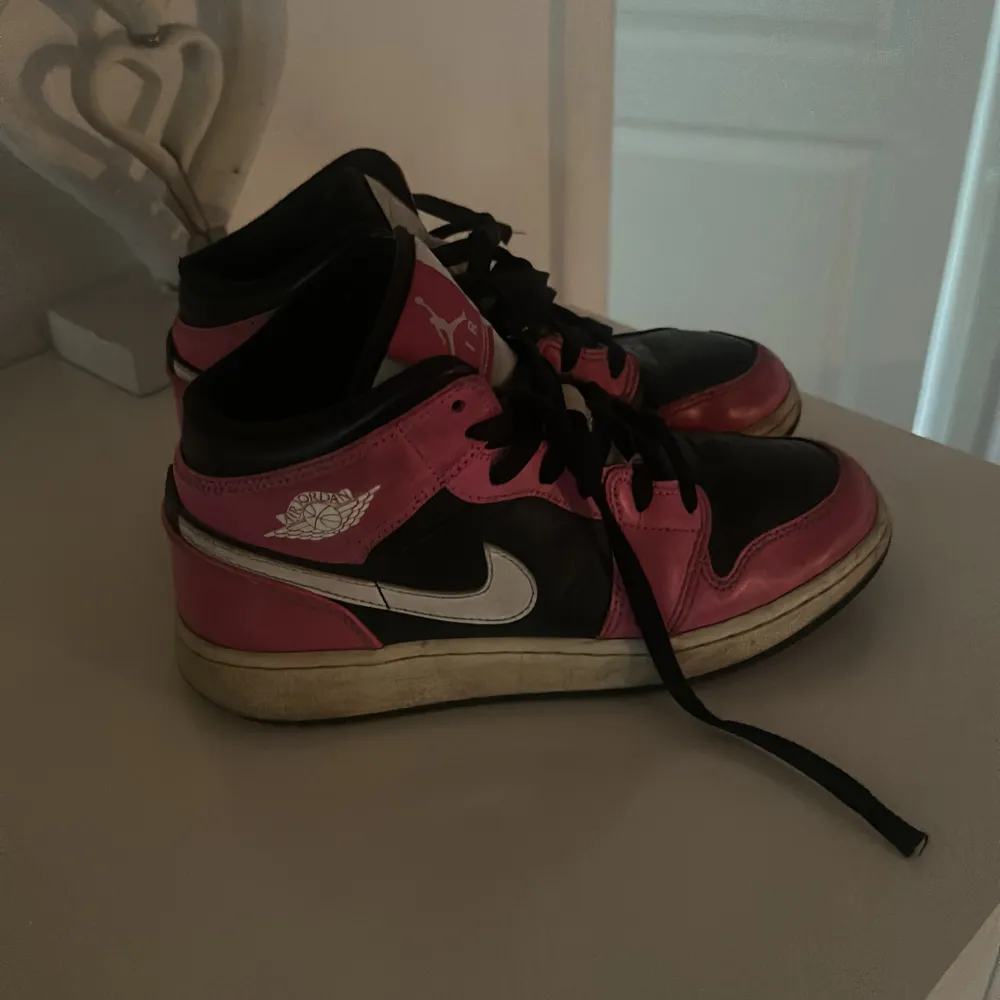 Säljer ett par coola Nike Air Jordans i svart och rosa. De har en klassisk design med snörning och en vit sula. Perfekta för både vardag och fest! Skorna är i bra skick med lite slitage på sulan.. Skor.