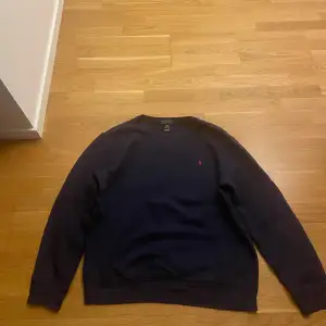 Säljer en klassisk mörkblå sweatshirt från Polo Ralph Lauren i storlek XL. Tröjan har en röd broderad logga på bröstet och är i mycket bra skick. Perfekt för höst och vinter, med långa ärmar och en bekväm passform. Passar både till vardags och lite mer avslappnade tillfällen.