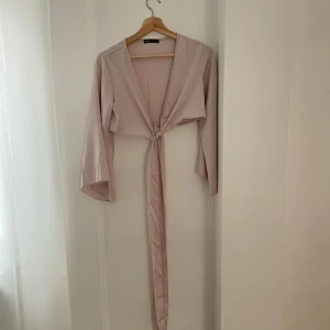 Beige knytblus med vida ärmar - Säljer en superfin beige blus med knytning framtill. Den har långa, vida ärmar som ger en elegant touch. Perfekt för både vardag och fest! 💫