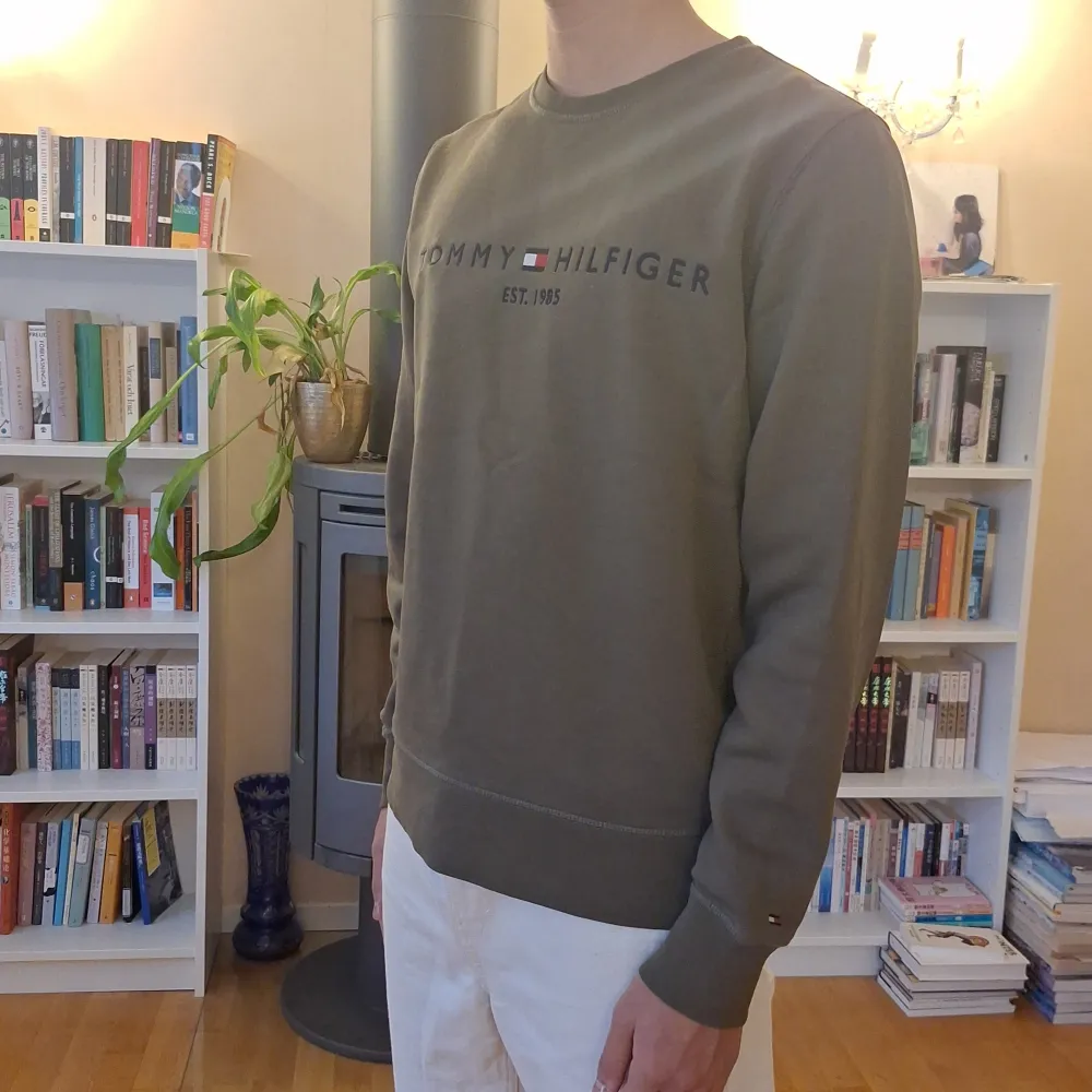 Säljer en snygg olivgrön sweatshirt från Tommy Hilfiger i storlek M. Tröjan har ett klassiskt tryck med märkesloggan på bröstet och är i mycket bra skick. Perfekt för både höst och vår, med långa ärmar och mjukt material. Passar till både jeans och chinos! Skick: 8/10. Tröjor & Koftor.