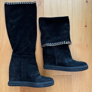 Mockastlövlar Casadei säljes - Svarta mockastövlar med mjuka vikbara skaft. Platåsula och kedja högst upp. Sparsamt använda. Nypris 7000 kr.