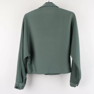 Grön skjorta från Wera - Säljer en stilren grön skjorta från Wera. Skjortan har en klassisk krage och knappar framtill. Den är långärmad och har en elegant, enkel design som passar perfekt för både vardag och fest. Materialet känns mjukt och bekvämt. Nypris: 499kr.