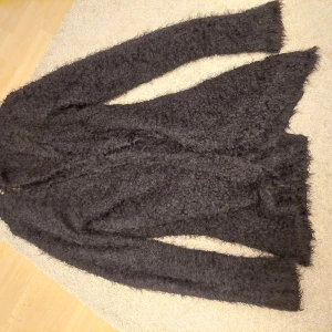 Mysig kofta - Stor svart lurvig mysig kofta. Är en barn storlek men kan även ha den som vuxen, är som L/M. Har gått sönder mitt i ärmen så det har blivit som ett stort hål, men kan enkelt fixas.