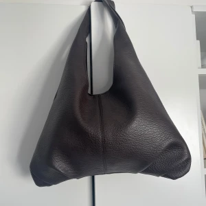 Mellanstor axelremsväska  - En medelstor väska som passar bra till typ allt. Den är mörkbrun utan några fack inuti. Har används ett fåtal gånger.  