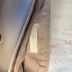 Läder väska  - Ur fin Väska ifrån H&M, färgen är ljus begie & vit. Kan användas med band och utan. Priset är förhandlingsbart!!💗