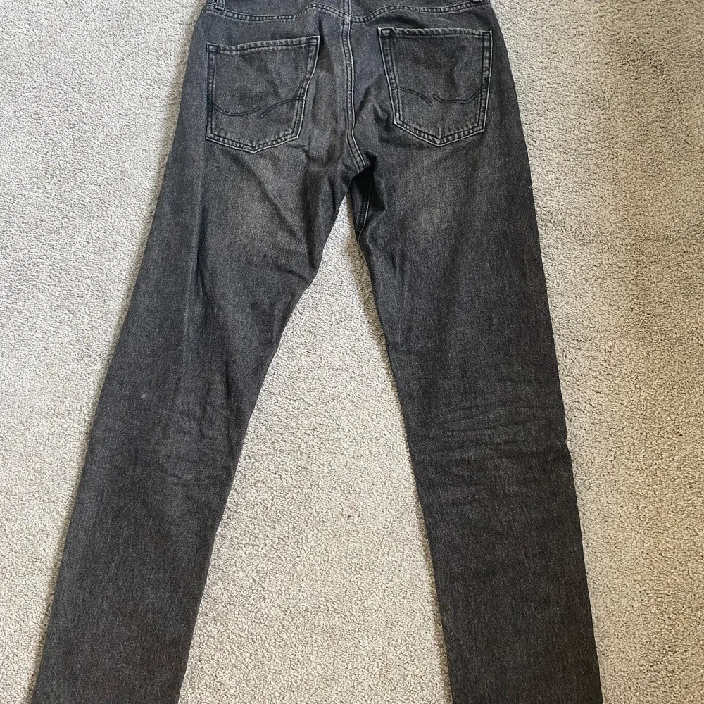 Säljer ett par grå jeans från Jack & Jones i modellen Loose/Chris. De har en loose passform och är perfekta för en avslappnad stil. Jeansen har en klassisk femficksdesign och är tillverkade i slitstarkt denim. Perfekta för både vardag och fest!. Jeans & Byxor.