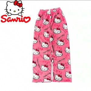 Rosa Hello Kitty byxor från Sanrio - Mysiga rosa byxor med Hello Kitty-motiv från Sanrio. Byxorna har ett lekfullt mönster med den ikoniska katten och är perfekta för en avslappnad dag hemma. De är gjorda i ett mjukt material som känns skönt mot huden.