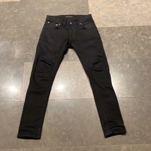 Svarta jeans från Nudie Jeans - Snygga svarta jeans från Nudie Jeans med en klassisk femficksdesign. De har en smal passform och är tillverkade i ett slitstarkt material. Perfekta för en stilren look.