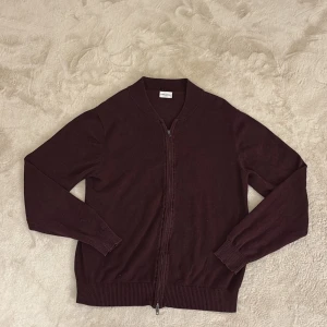 Vinröd kofta från John Henric - Säljer en stilren vinröd stickad kofta från John Henric. Koftan har en dragkedja framtill och ribbade muddar vid ärmslut och nederkant. Perfekt för kyligare dagar. Hör av dig vid funderingar och pris kan diskuteras vid snabb affär mvh Malte 