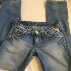 Blå jeans från Diesel - Snygga blå jeans från Replay  med en klassisk femficksdesign och knappgylf. Jeansen har en lätt tvättad look och raka ben. Perfekta för en avslappnad stil.