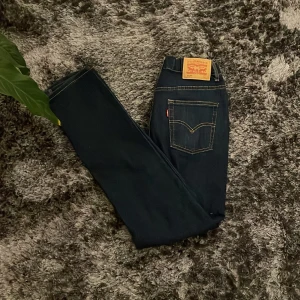 Levi's 512 Slim Taper Jeans - Snygga mörkblå Levi's 512 Slim Taper jeans med klassisk femficksdesign och guldfärgade sömmar. Perfekta för en stilren look med en smal passform som smalnar av vid anklarna. Ikonisk läderpatch baktill.