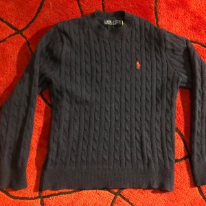 Mörkblå stickad tröja från Polo Ralph Lauren - Säljer en snygg mörkblå stickad tröja från Polo Ralph Lauren med det klassiska broderade logotypen i rött på bröstet. Storlek s 