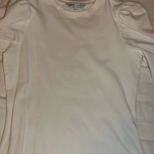 Vit långärmad topp från ONLY - Säljer en stilren vit långärmad topp från ONLY i storlek XS. Toppen har puffiga ärmar som ger en trendig touch. Perfekt för att matcha med olika outfits. Hör av dig vid intresse! 🤍