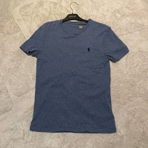 Blå t-shirt från Ralph Lauren - Snygg blå t-shirt från Ralph Lauren med en liten broderad logga på bröstet. Perfekt för en avslappnad stil. Gjord i mjukt bomullsmaterial för extra komfort.