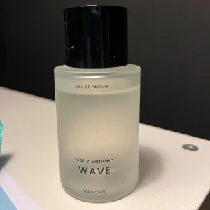 Molly Sandén Wave Eau de Parfum - Säljer en elegant Molly Sandén Wave Eau de Parfum från Nordicfeel. Flaskan är frostad och cylindrisk med en stilren svart kork. Perfekt för den som söker en fräsch och modern doft.
