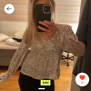 Glittrig tröja från Gina Tricot - Säljer en glittrig tröja från Gina Tricot med v-ringning. Perfekt för att lysa upp vilken outfit som helst. Tröjan har långa ärmar och är täckt med paljetter som ger en festlig känsla. Passar bra till speciella tillfällen eller när du vill sticka ut.