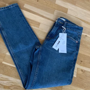 Blå jeans från Gina Tricot - Snygga blå jeans från Gina Tricot med klassisk design. De har en dragkedja och knapp framtill. Perfekta för en avslappnad stil. Storkek 32 