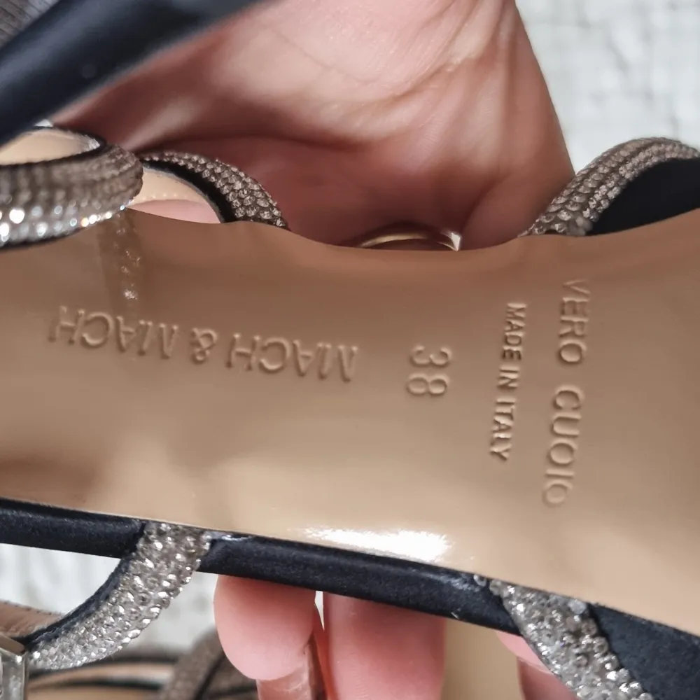 Endast använda en gång inomhus! I perfekt skick utan defekter. Eleganta svarta klackskor från Mach & Mach med spetsig tå och glittrande rosett. Skorna har en dekorativ rosett framtill, perfekta för att sätta en glamorös touch på din outfit. Nypris 11 000 kr. . Kengät.