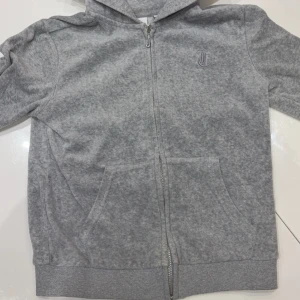 Grå hoodie från Juicy Couture - Grå hoodie från Juicy Couture med dragkedja och fickor framtill. Inget tryck på ryggen. I storlek 12/13 i barn modellen.