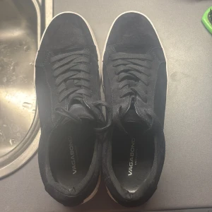 Svarta Vagabond  - Snygga svarta sneakers från Vagabond i mocka med klassisk snörning och vit sula. Storlek 42 men passar även 43. Perfekta för både vardagen och till fester. Nypris (1400 kr). Skick 9/10. Priset går även att diskutera