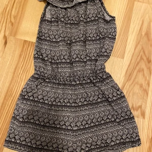 Mönstrad byxdress från Kappahl - Säljer en snygg mönstrad byxdress från Kappahl i svart och vitt. Klänningen har ett geometriskt mönster och är ärmlös med en elastisk halslinning. Perfekt för en avslappnad stil. 🖤