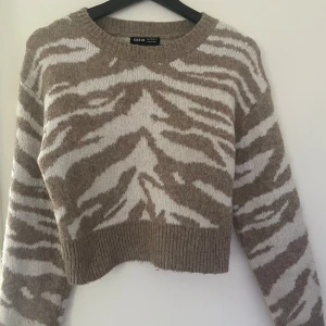 Beige och vit stickad tröja - Säljer en beige och vit stickad tröja från Shein med zebramönster. Tröjan är croppad och har långa ärmar. Storlek S men sitter fint på de med Xs också. Använd några enstaka gånger men i väldigt fint skick!
